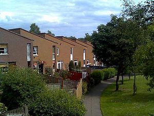 Contemporary staggered terraced housing with mono-pitch roofs set in mature landscaping
